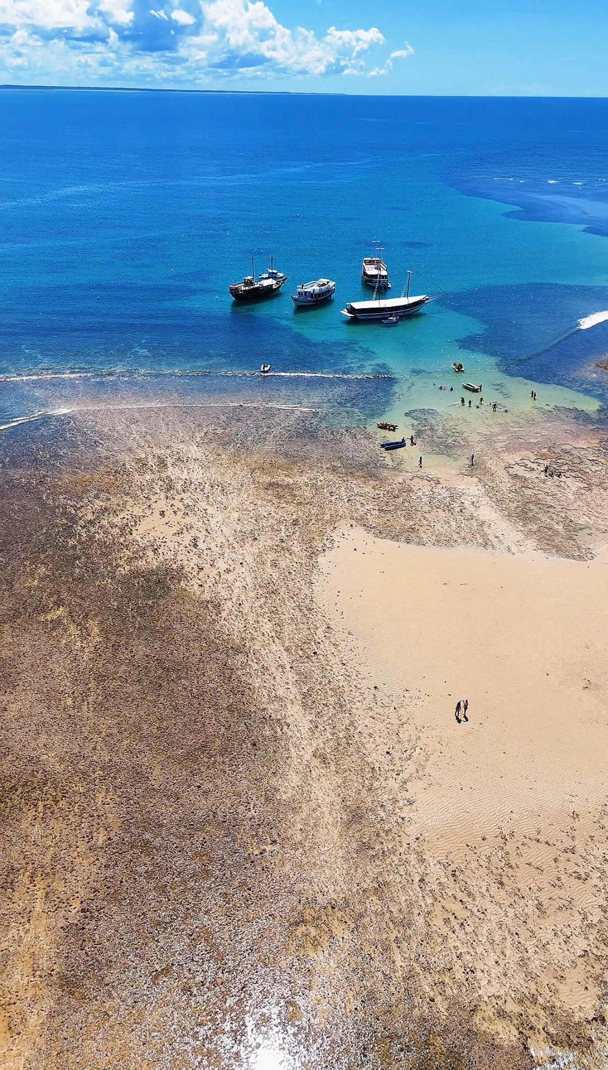 Barcos e piscinas naturais vistos do alto em Recife de Fora