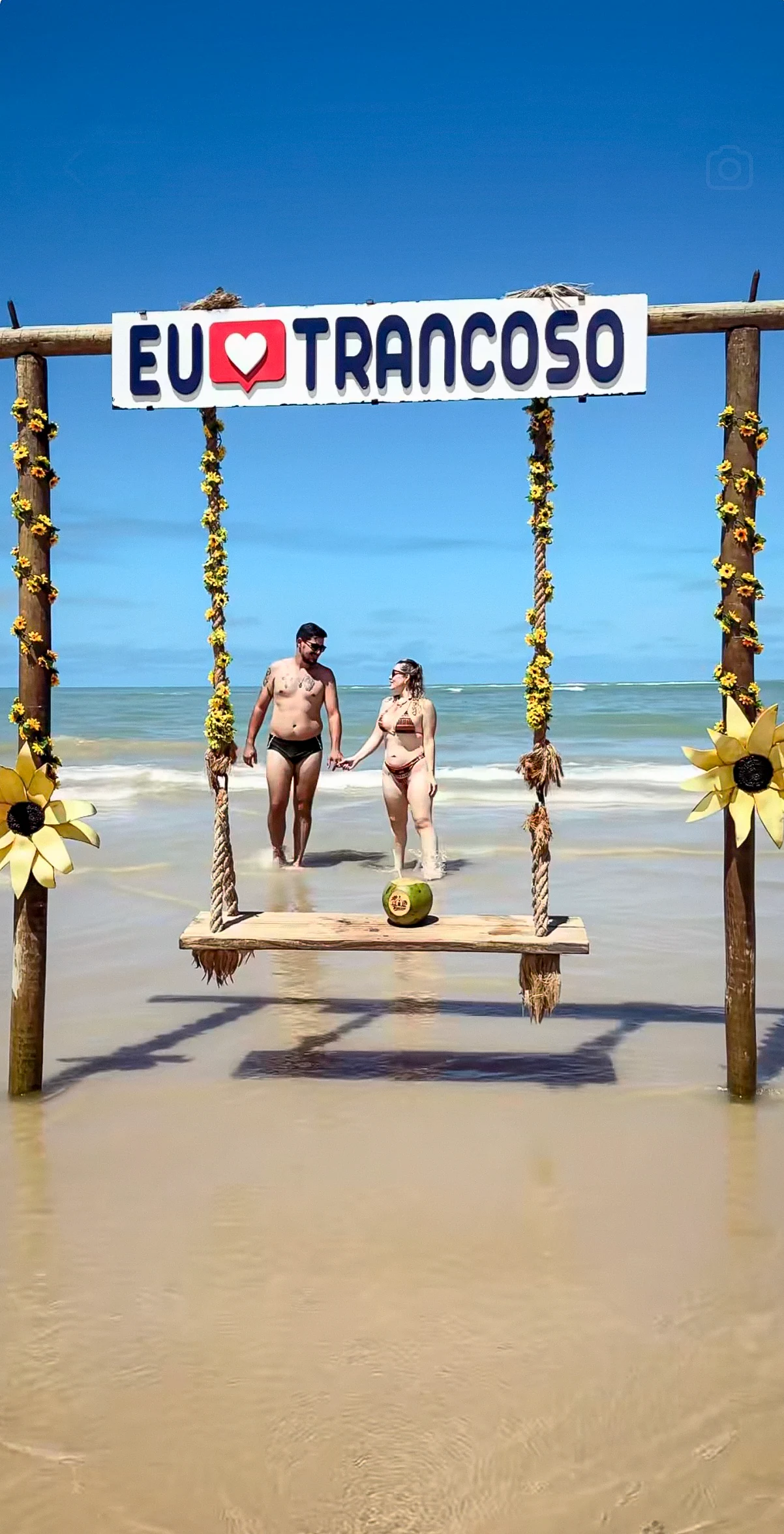 Casal passeando sob o balanço Eu amo Trancoso